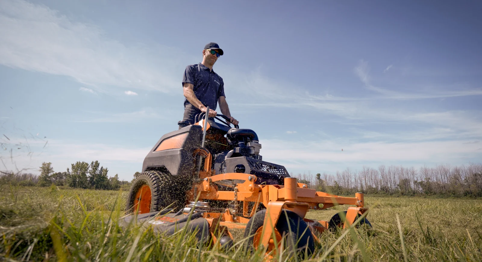 Commercial stand-on mower working in tall grass