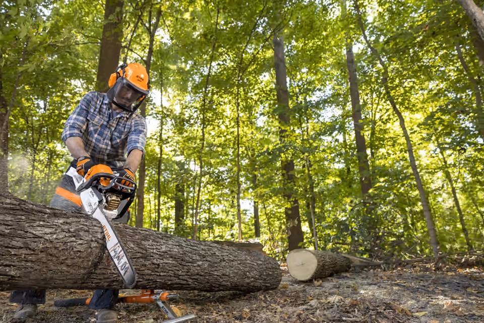 STIHL chainsaw cutting a supported log outdoors