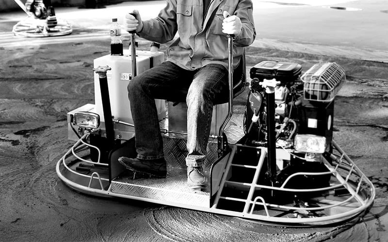Operator using an engine-powered ride-on concrete trowel
